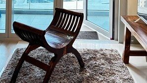 A room with a large window, a wooden chair, and a flat-screen TV on a wooden stand. - Uptown Parksuites Tower Two (Taguig)