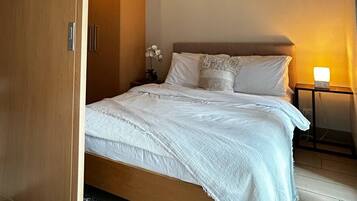 A bedroom with a bed, a nightstand, a lamp, and a wardrobe.