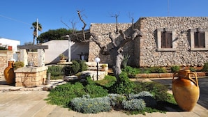 A stone building with a garden, a large vase, and a small tree.