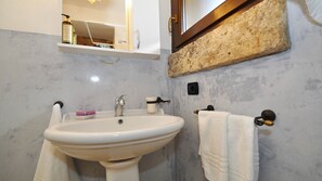 Ein Badezimmer mit einem weißen Waschbecken, einem Spiegel, einem Handtuchhalter und einem Ablagebereich für Toilettenartikel.