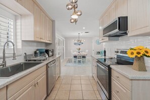 A modern kitchen with stainless steel appliances, wooden cabinets, and a central island with seating. - 'Coral Breeze' home Near Siesta Key! Pool (Sarasota)
