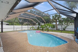 An outdoor swimming pool with a covered area, surrounded by a fence and greenery. - 'Coral Breeze' home Near Siesta Key! Pool (Sarasota)
