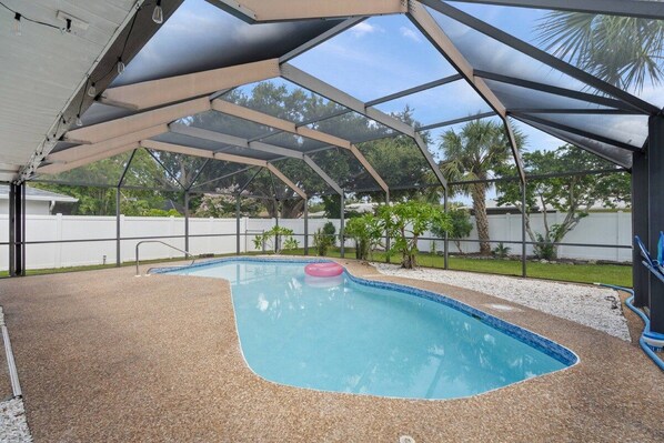 An outdoor swimming pool with a covered area, surrounded by a fence and greenery. - 'Coral Breeze' home Near Siesta Key! Pool (Sarasota)