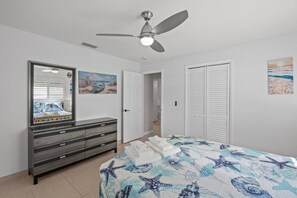 A bedroom with a bed, a dresser, a ceiling fan, and a door leading to another room. - 'Coral Breeze' home Near Siesta Key! Pool (Sarasota)