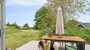 A deck with a wooden table, chairs, and a large umbrella. - Holyday home in beatiful Vang (Hasle)
