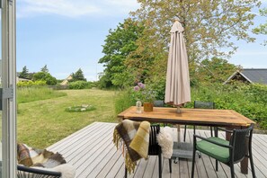 A deck with a wooden table, chairs, and a large umbrella. - Holyday home in beatiful Vang (Hasle)