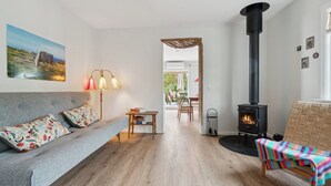 A cozy living room with a sofa, a table, a chair, a fireplace, and a painting on the wall. - Holyday home in beatiful Vang (Hasle)