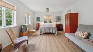 A bedroom with a bed, a sofa, a chair, a TV, a wardrobe, and a window. - Holyday home in beatiful Vang (Hasle)