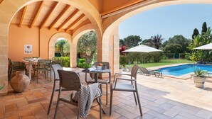 Eine Außenpatio mit Pool, überdachter Sitzgelegenheit und Blick auf den Poolbereich.
