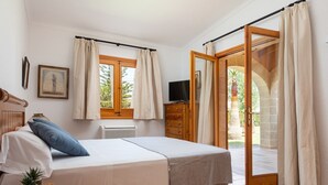 Ein Schlafzimmer mit einem Bett, einem Fernseher, einem Schminktisch und einem Fenster mit Vorhängen.