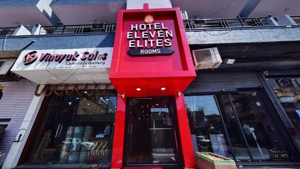 Hotel Eleven Elites with a prominent red entrance sign, a visible storefront with 'Vimayak Sales' and 'Laminex Gallery' signage, and a clear glass facade. - Hotel Eleven Elites (Kota)