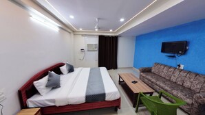A hotel room with a bed, a sofa, a TV, and a small table. - Hotel Eleven Elites (Kota)
