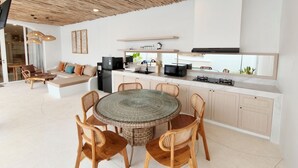 Eine moderne Küche mit einem runden Glastisch, Holzsesseln und einem Deckenventilator.