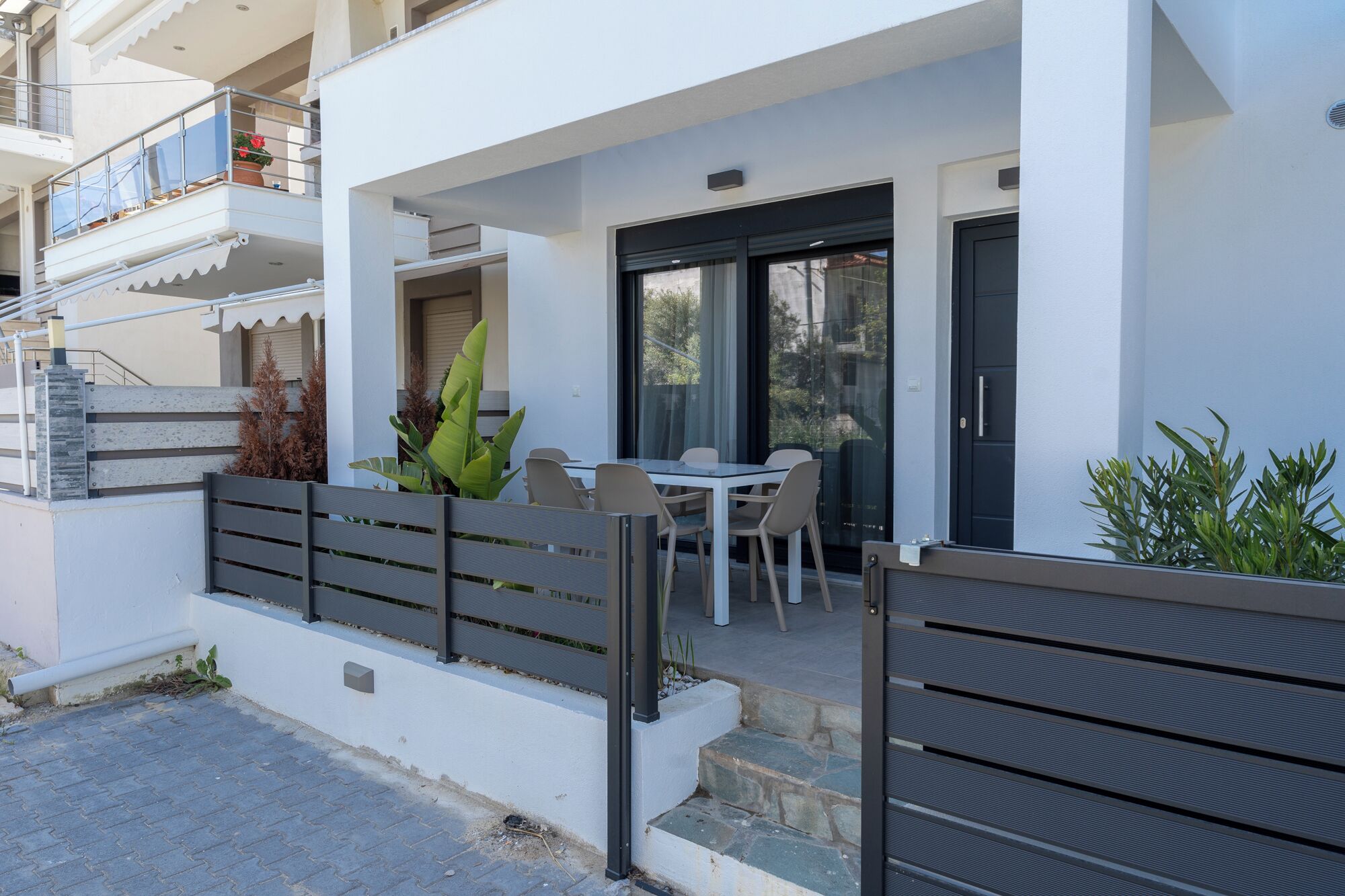 Un bâtiment moderne doté d’un balcon, d’une table avec des chaises et d’une porte.