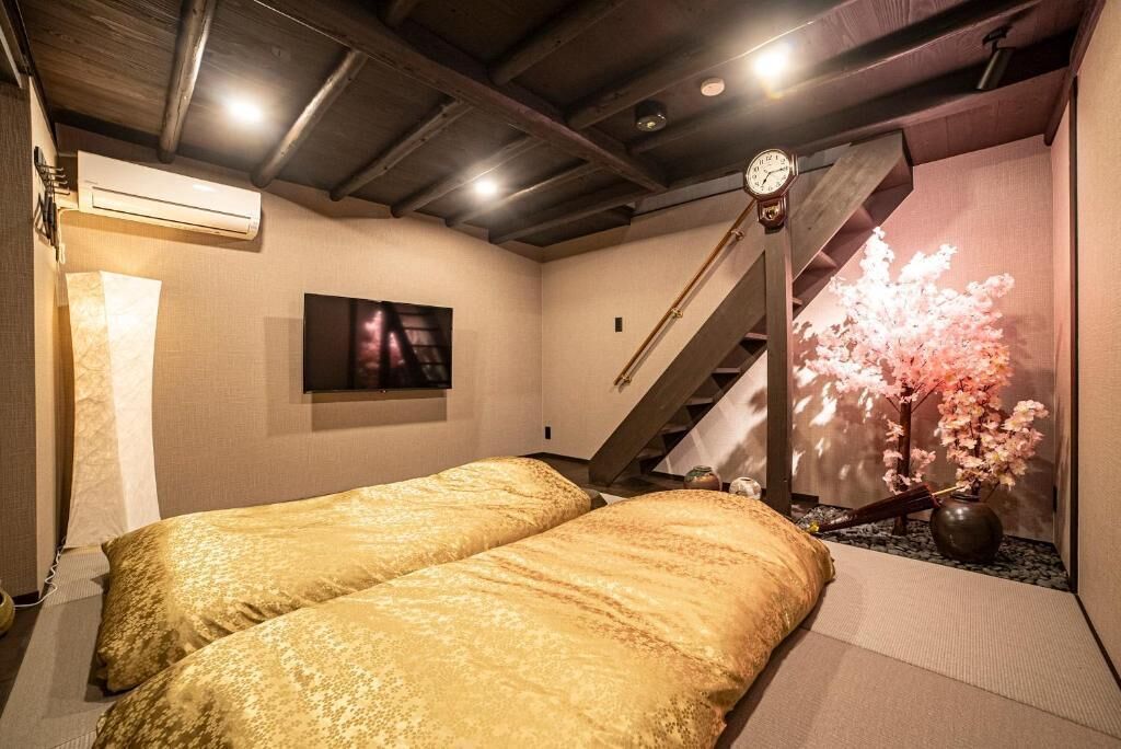 A hotel room with two beds, a staircase, a wall-mounted clock, and a projection of cherry blossoms.