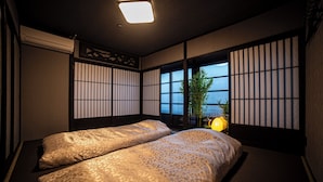 A traditional Japanese-style room with tatami flooring, shoji screens, and a view of the water. - Oyado Kinokuniya Kagomachi (Nagasaki)