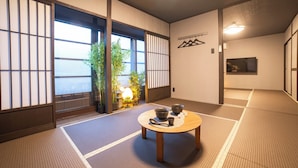 A traditional Japanese room with tatami flooring, a low wooden table with bowls, and a view through shoji screens. - Oyado Kinokuniya Kagomachi (Nagasaki)