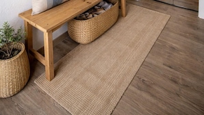 A wooden bench with woven baskets, a wall-mounted anchor decoration, and a hanging tassel.