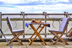 Relax in a serene outdoor setting with a table and chairs overlooking a calm body of water.