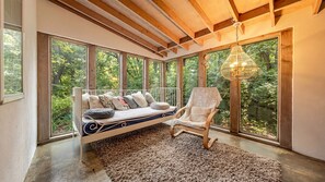 Una habitación con cama, una silla y amplios ventanales que ofrecen vistas al exterior.