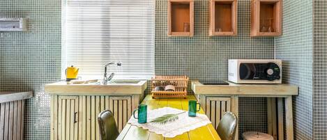 A kitchen with a wooden countertop, a sink, a microwave, and wooden cabinets.