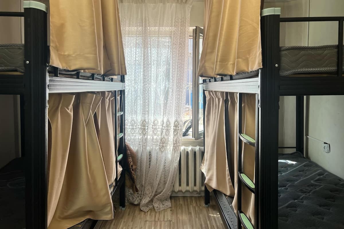 Ein Schlafzimmer mit Etagenbetten, Vorhängen, einem Heizkörper und einem Fenster mit Spitzenvorhängen.
