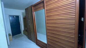 Een hal met een houten garderobe, een blauwe deur en een betegelde vloer.