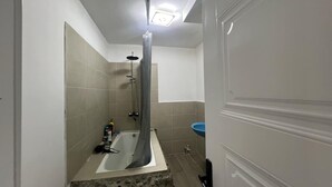 Een badkamer met een bad, douche en een blauwe wastafel.