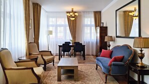 A well-lit living room with a sofa, chairs, a coffee table, and a dining area.
