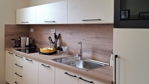 A modern kitchen with white cabinets, a stainless steel sink, and wooden flooring.