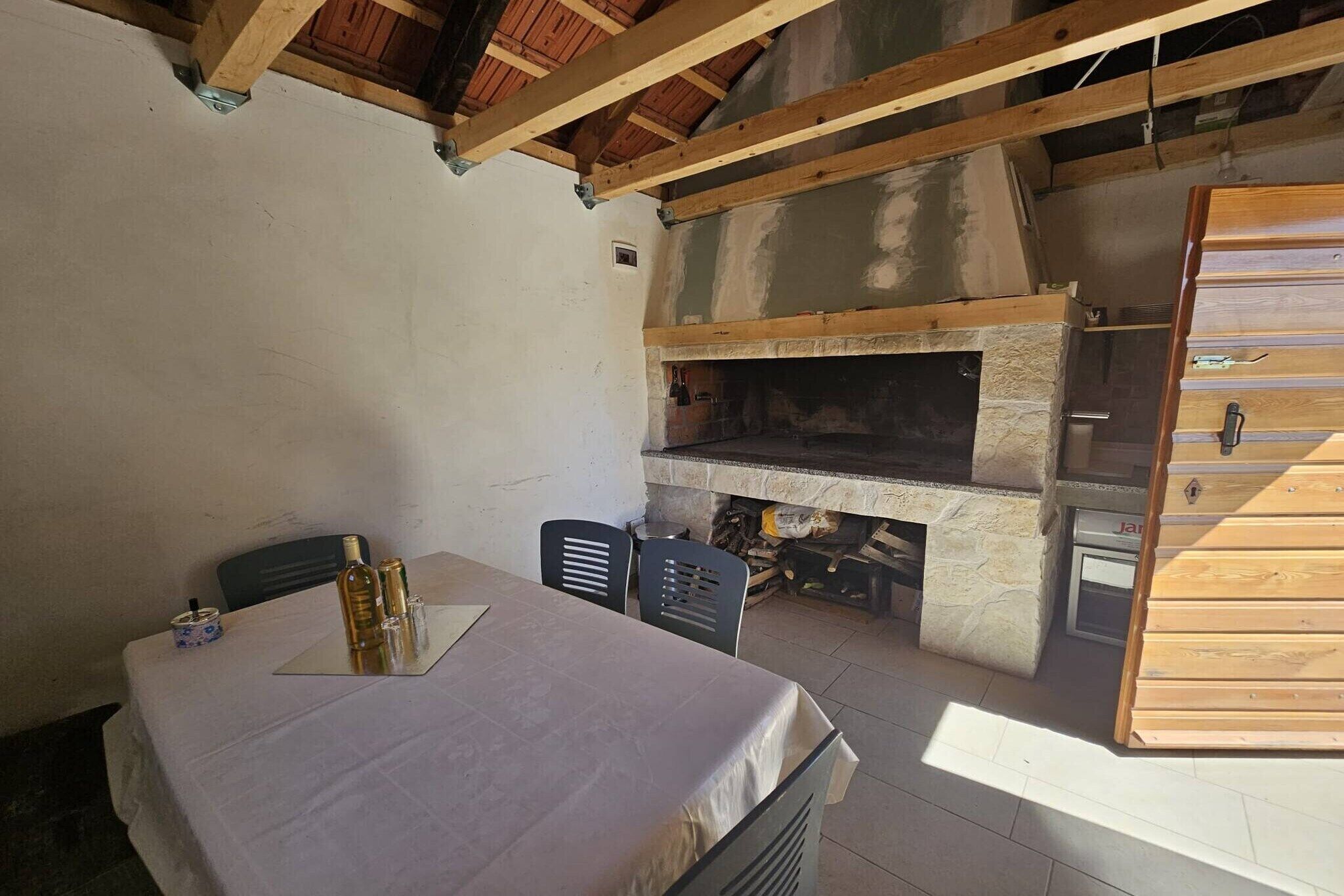Una habitació rústica amb una llar de pedra, una taula de dinar amb cadires i un armari de fusta.