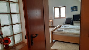 A bedroom with a wooden bed, a window, a chair, and a desk. - Room 'Zum Schlossberg' with Mountain View and Balcony (Vogtsburg)