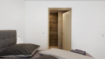 A modern bedroom with a bed, a bedside table, and a wooden door leading to a shower area.