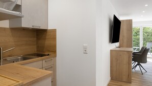 Une cuisine moderne dotée d’un plan de travail en bois, d’un évier en acier inoxydable et d’un téléviseur encastré.