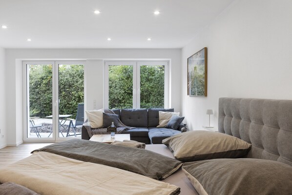 A modern living room with a sofa, a bed, and a dining area.