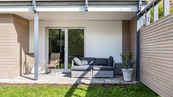 Un espace extérieur moderne aménagé avec un canapé, des fauteuils et une plante en pot.