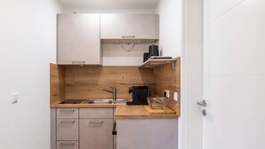 A compact kitchen with a wooden countertop, a sink, cabinets, and a coffee machine.