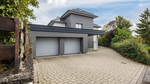 A modern house with a paved driveway, a garage, and a wooden fence.