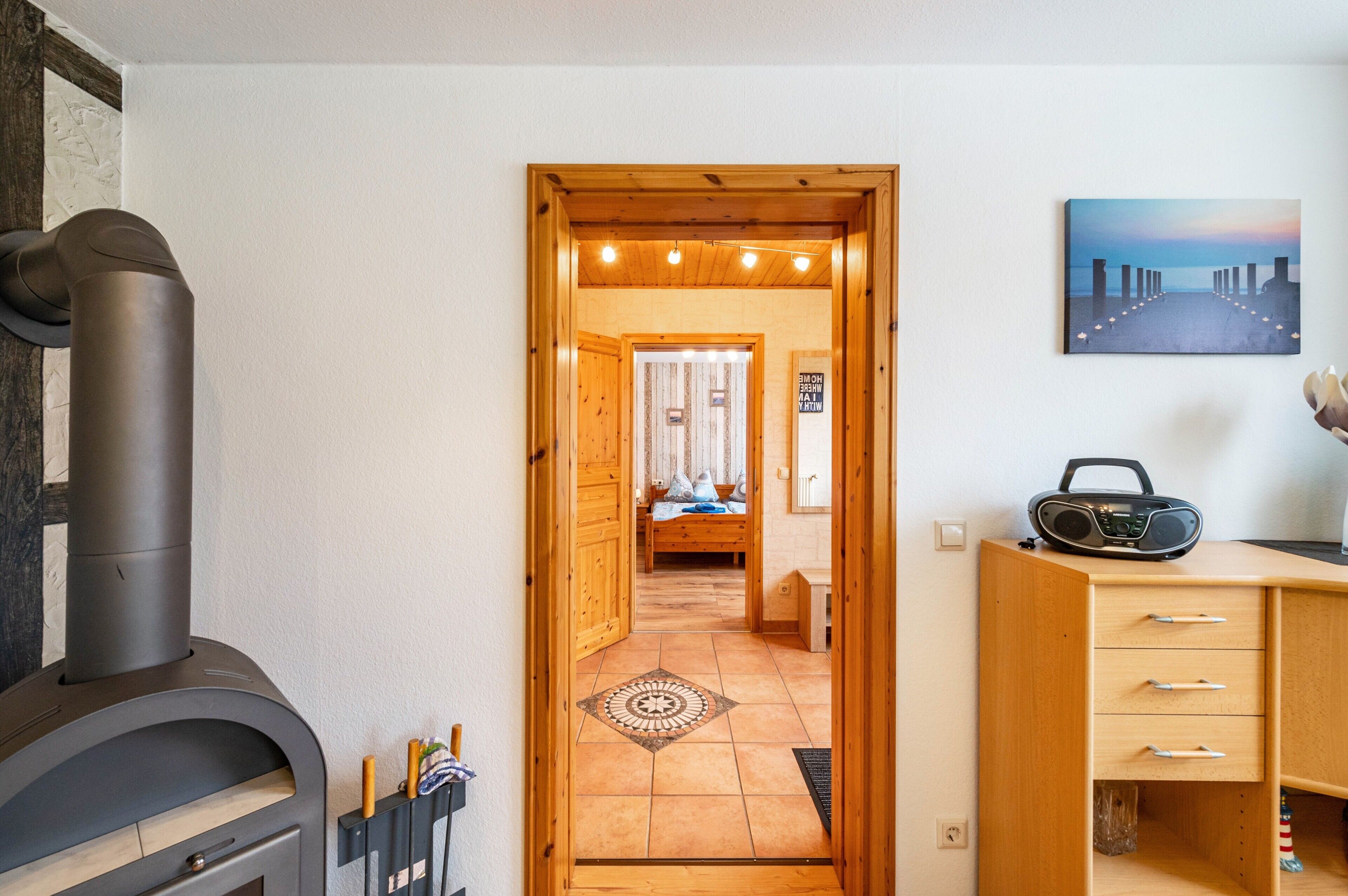 Ein Flur, der zu einem Schlafzimmer mit einem Bett, einem Holzschrank und einem Radio führt.
