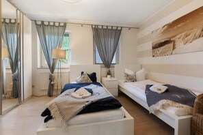 A bedroom with a bed, a sofa, a bedside table, a lamp, and a window with curtains.