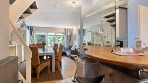 A modern kitchen with a wooden countertop, stainless steel appliances, and a dining area with a table and chairs.