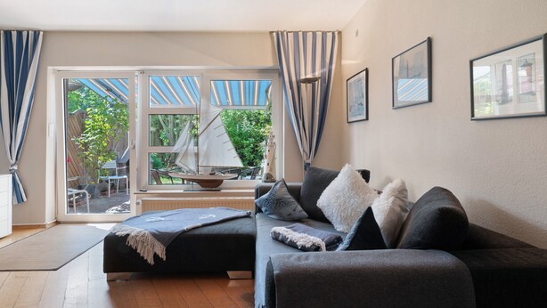 A modern living room with a sofa, a small table, and a view of a sailboat outside.