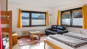 Una habitación con literas, un sofá, una mesita y vistas a un paisaje nevado a través de amplios ventanales.