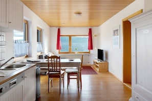 Una cucina con mobili in legno, un tavolo da pranzo, sedie e una finestra con tende.