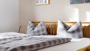 Ein Bett mit karierter Decke, zwei Kissen und einem hölzernen Kopfteil.
