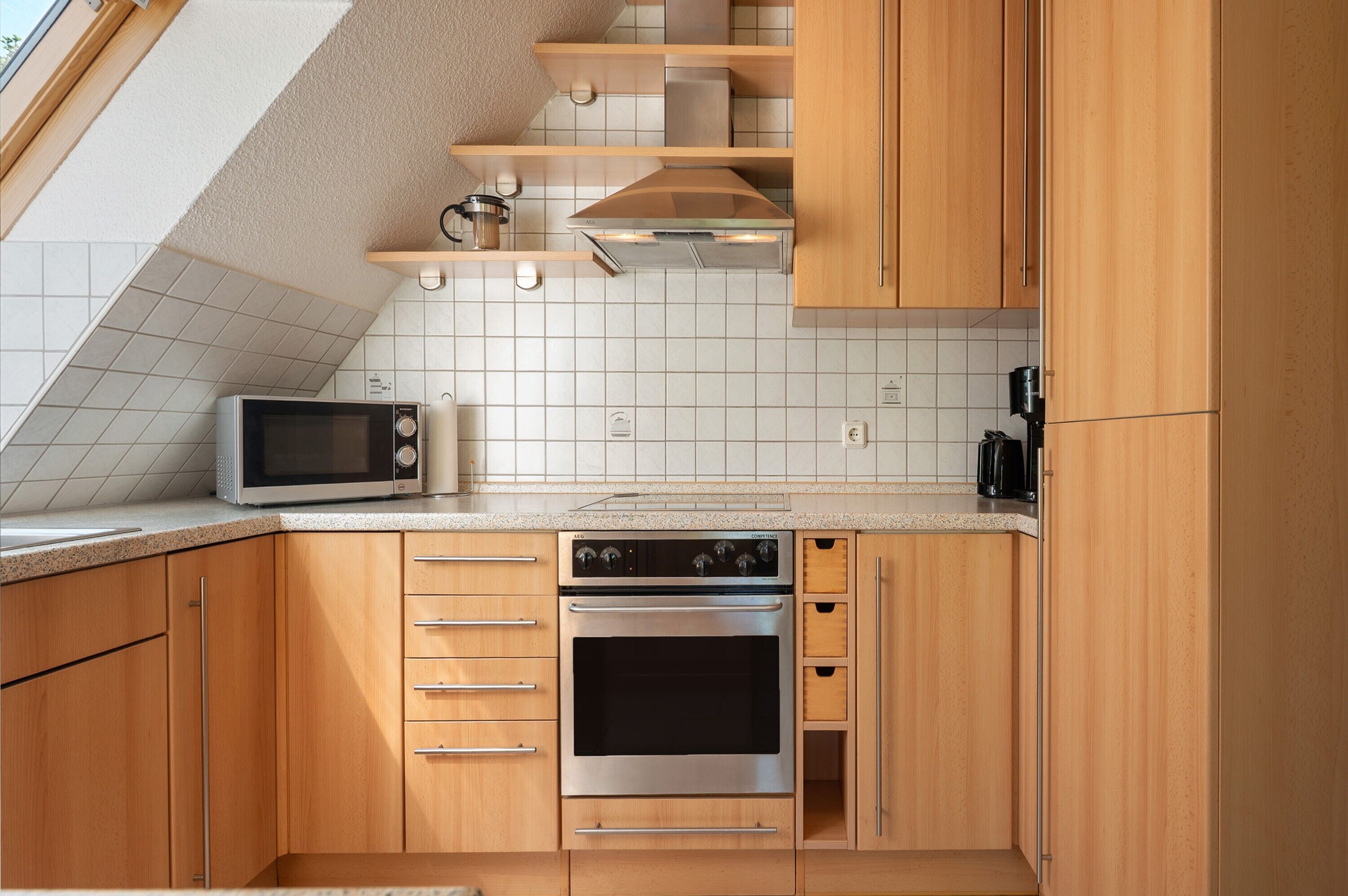 A kitchen with wooden cabinets, a microwave, an oven, and a coffee maker.