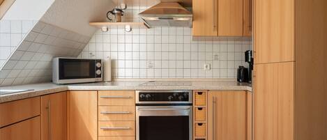 A kitchen with wooden cabinets, a microwave, an oven, and a coffee maker.