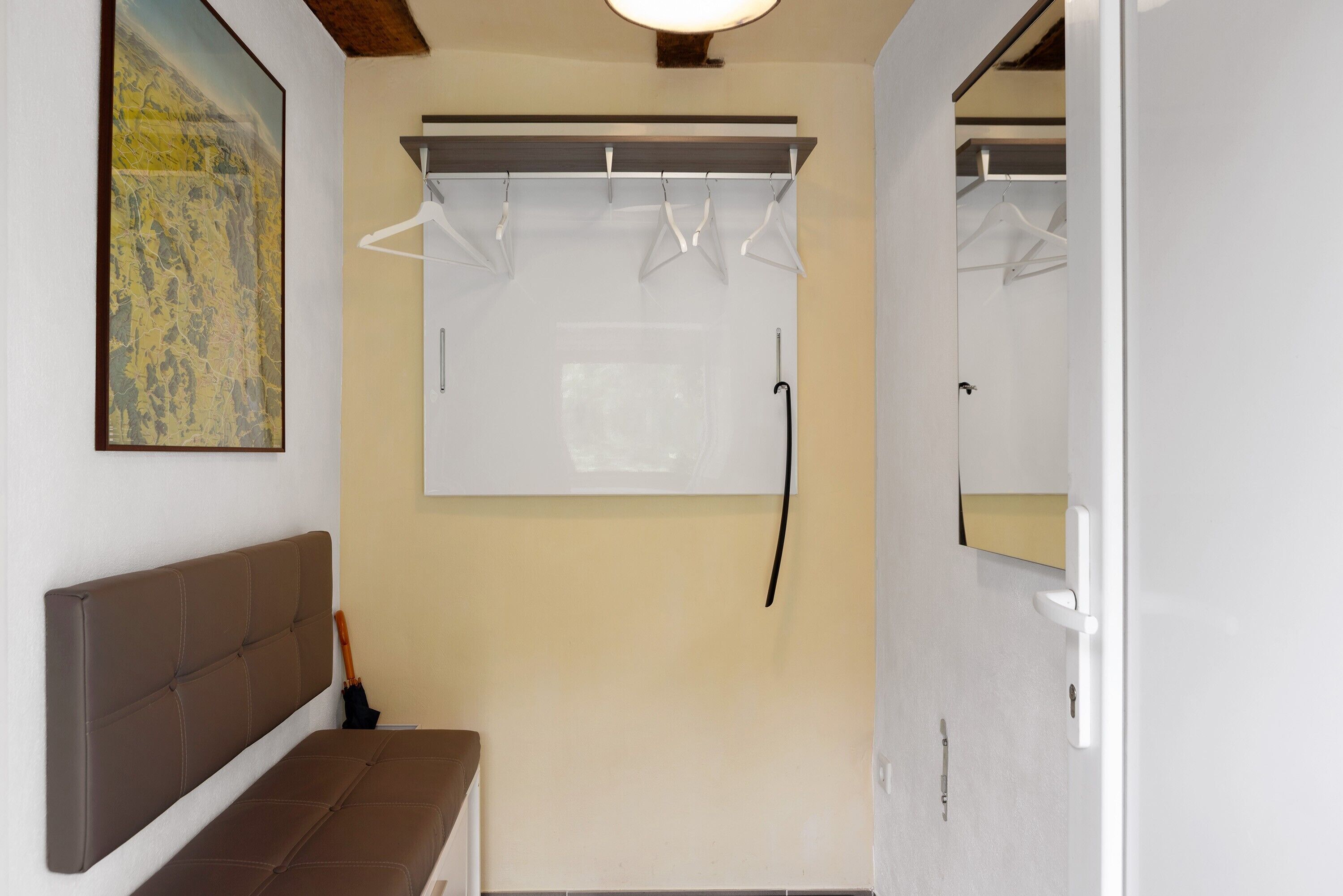 A bathroom with a bench, a towel rack, and a mirror.