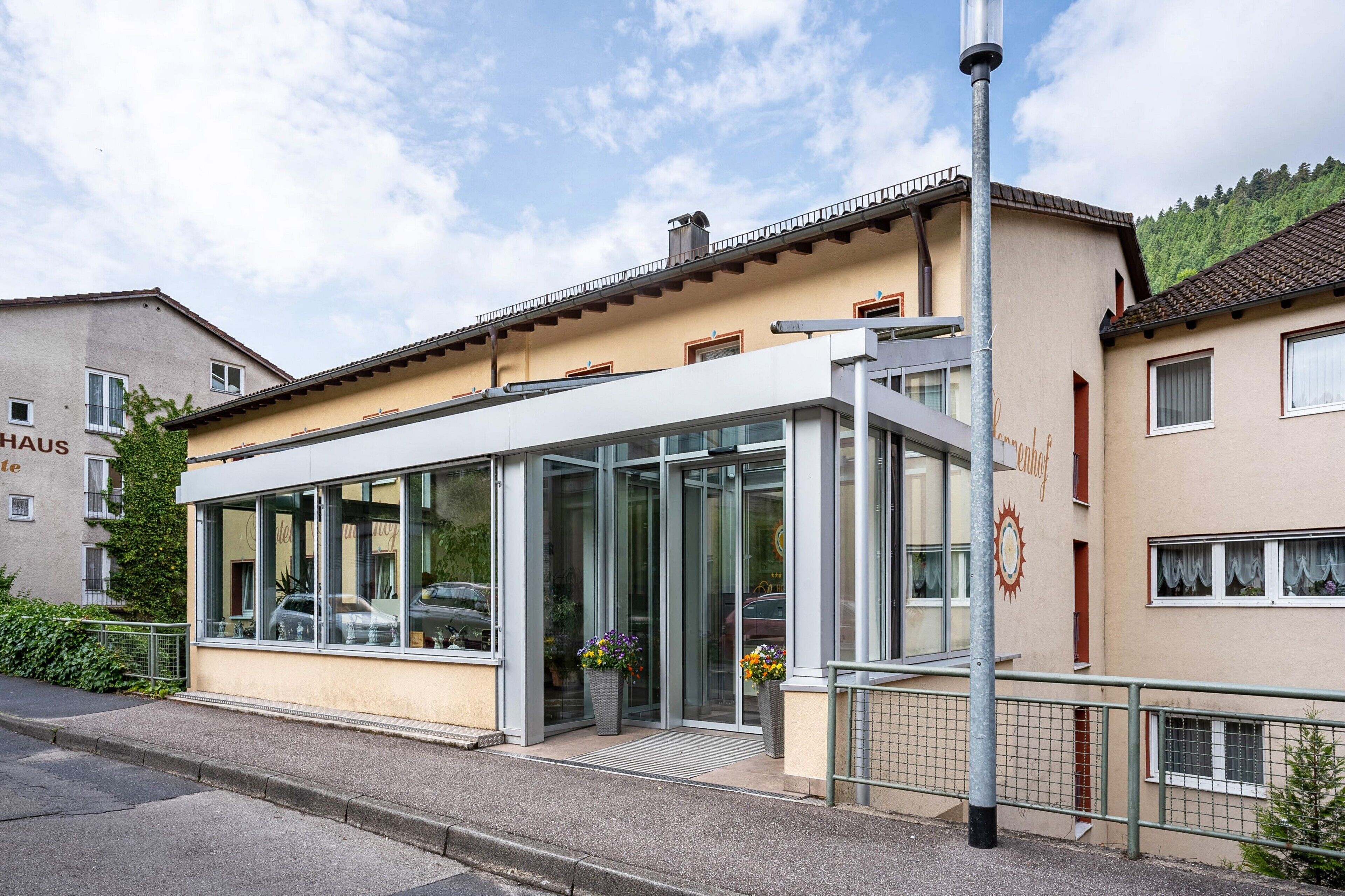 Ein modernes Gebäude mit großen Glasfenstern, einem Metallgeländer und einem Schild mit der Aufschrift 'Haus'.