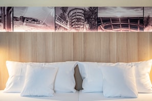 A bed with white pillows and a wooden headboard.
